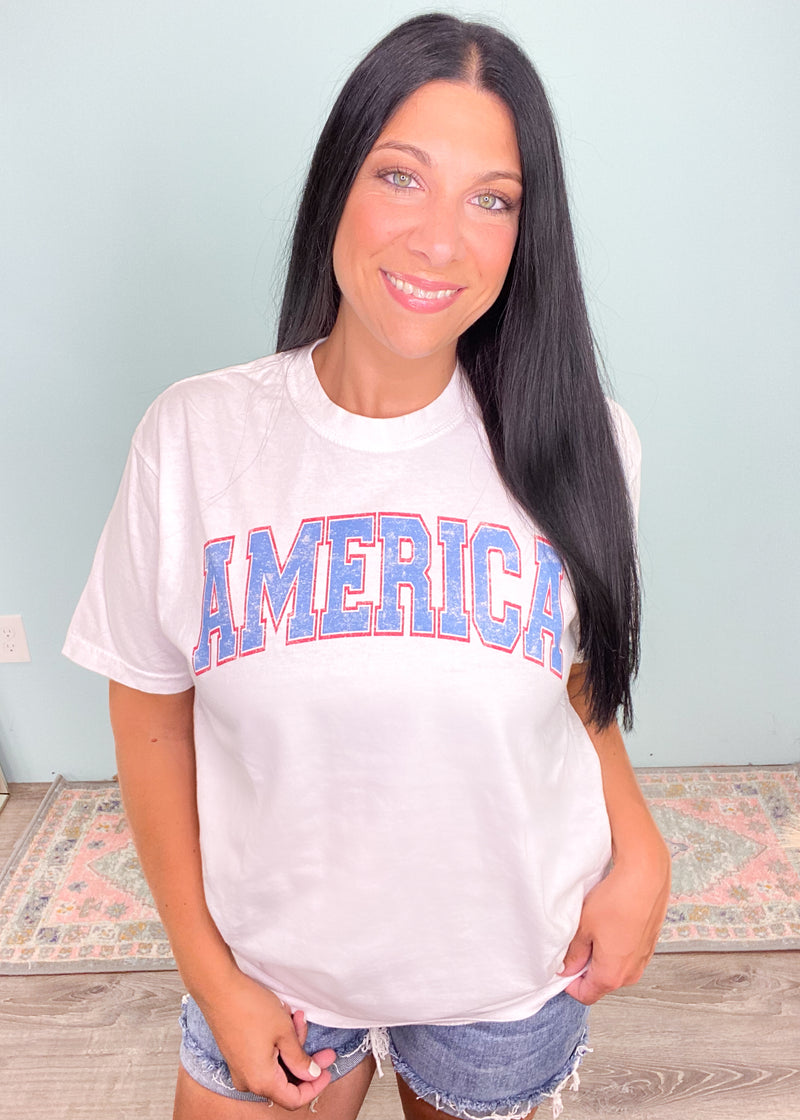 'America' White Comfort Tee Vintage Varsity Graphic-Show your American pride in comfort! This America tee shirt is ultra soft and moveable with a cute 'America' graphic in vintage varsity style lettering. -Cali Moon Boutique, Plainville Connecticut